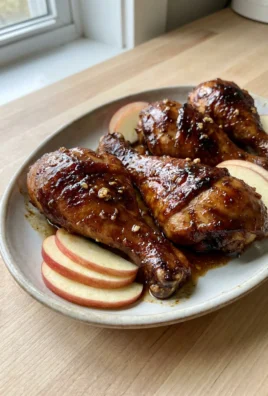 A close-up of broiled apple butter chicken drumsticks with a glossy, caramelized coating.