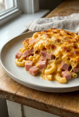 A 9x13 inch glass baking dish filled with cheesy ham macaroni before baking.