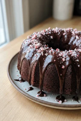 A side view of the finished bundt cake showing the dark glaze and candy cane topping.